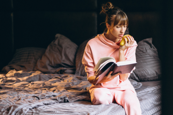 kvinne som sitter på sengen og leser og reflekterer over egne tanker og seksualitet