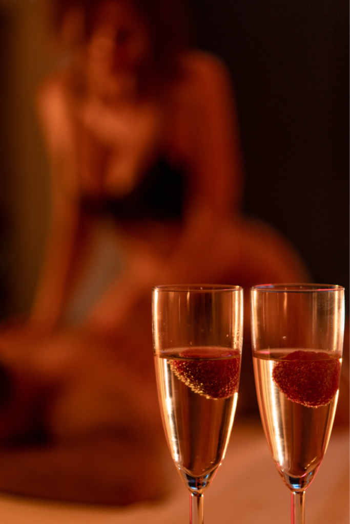 To glass med champagne og jordbær i varmt lys – romantisk stemning før en intim kveld