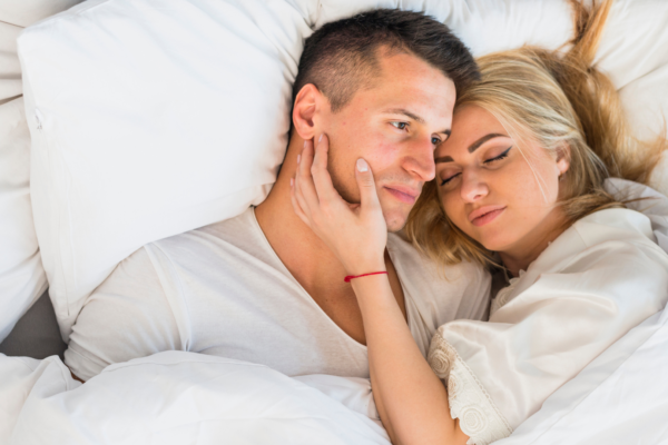 par som ligger tett sammen i sengen og viser nærhet og tillit i forhold